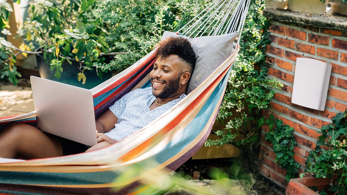man in hammock outdoors with laptop