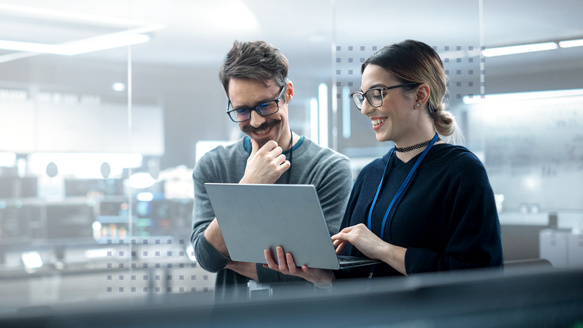Two smiling cowokers looking at a laptop together in an office setting