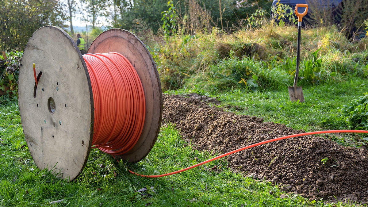 Cable drum with orange network cord on meadow field