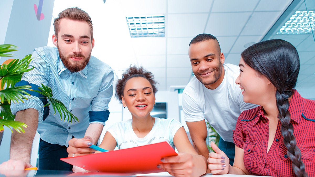 Smiling marketers having a meeting together while viewing a tablet