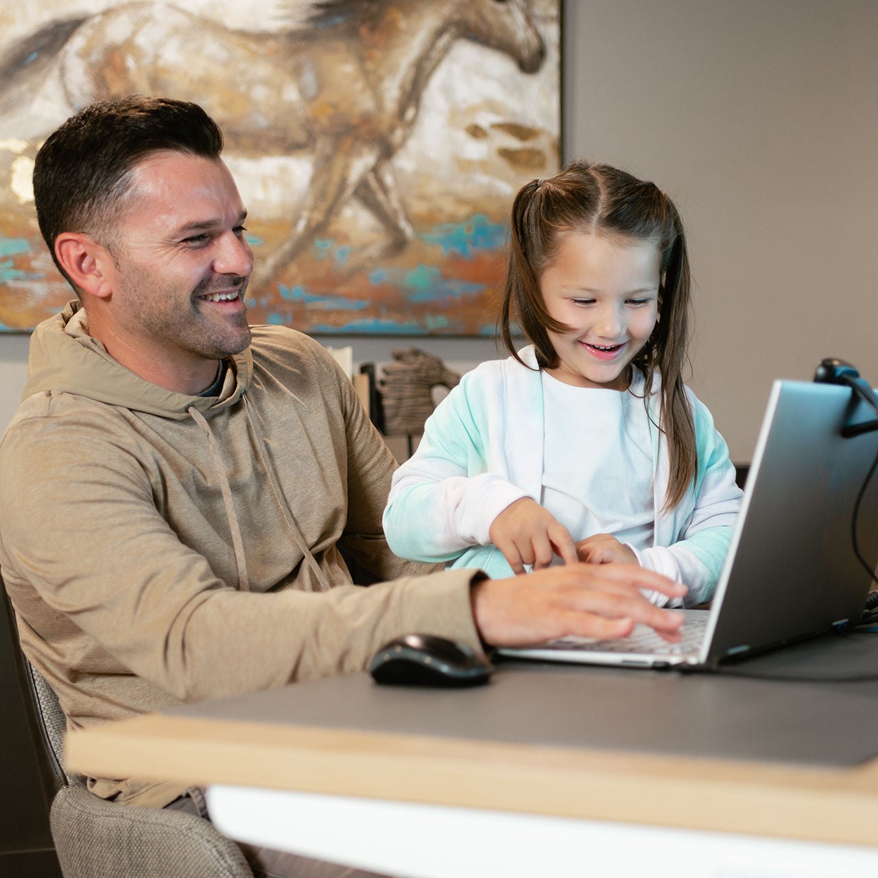 Father and daughter smiling while using a laptop