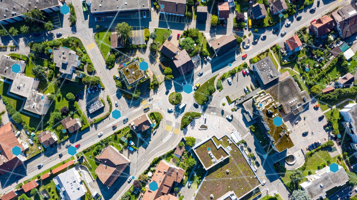 aerial-town-network-overlay. An aerial image of a small town with an abstract network icons overlay