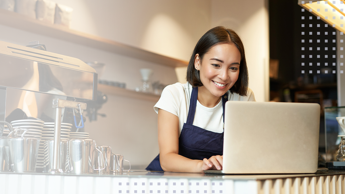 A female small business owner using a laptop protected with SmartBiz cybersecurity