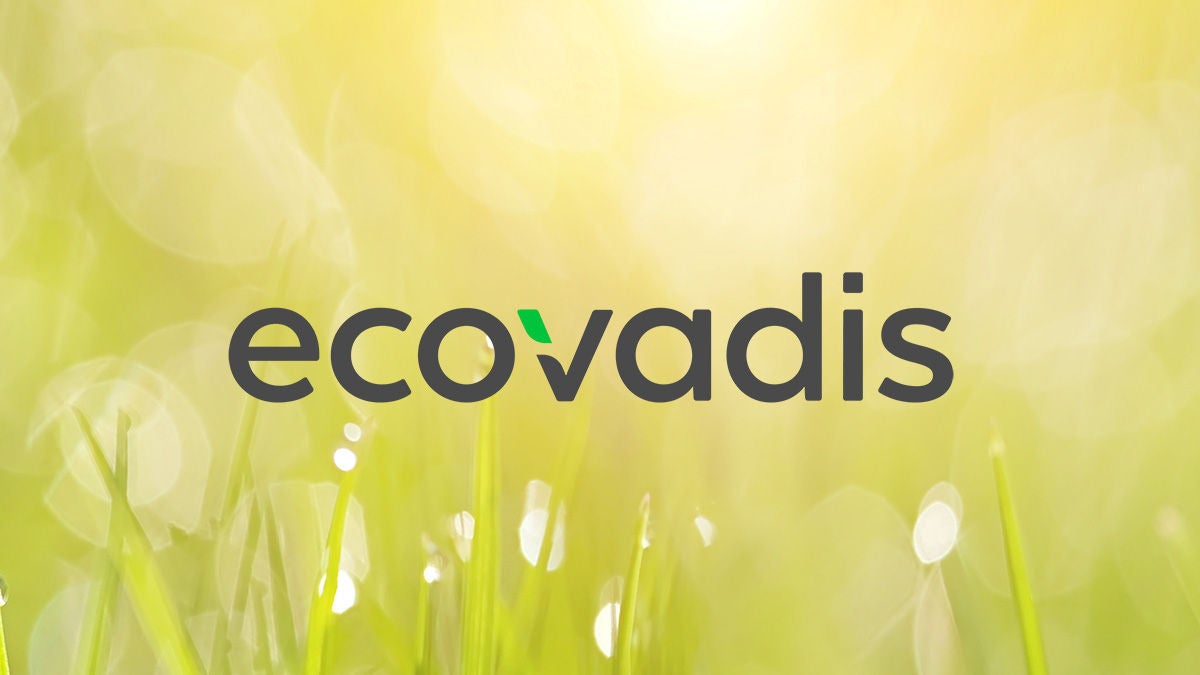 ecovadis logo with dew drops on green grass in the morning in the background