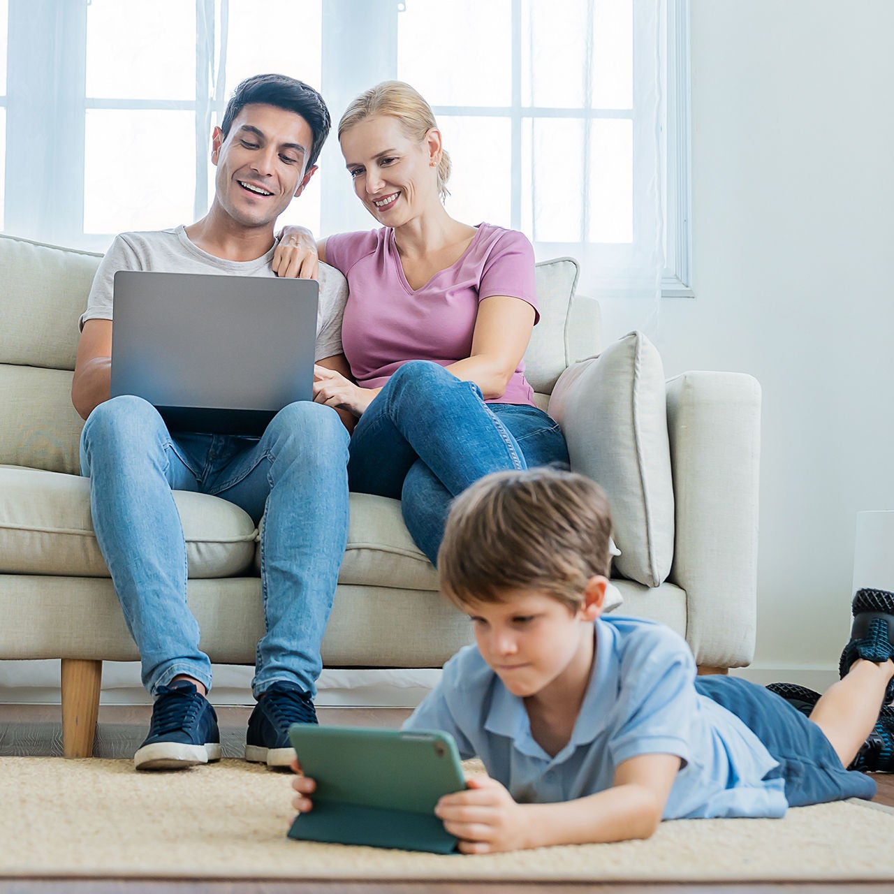 Parents and child using electronic devices at home