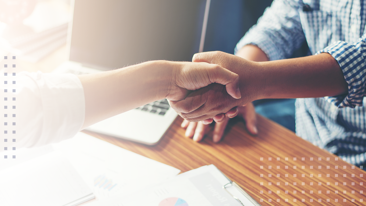 Two people shaking hands at a consultation meeting in an office