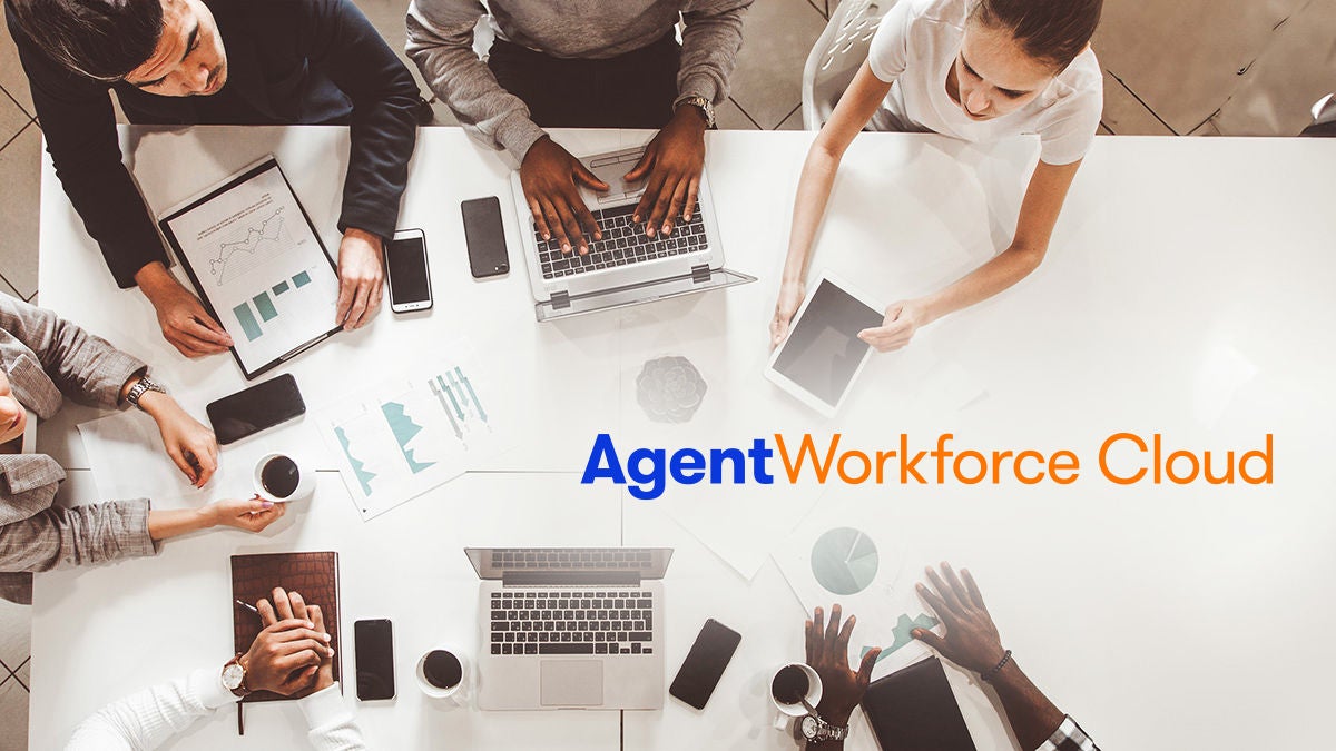 A diverse group of professionals gathers around a white table, working with laptops, tablets, and documents