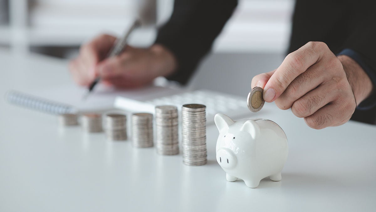 A man adding coins to a piggy bank