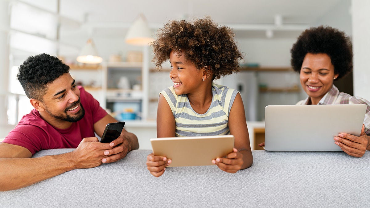 Smiling family at home with devices