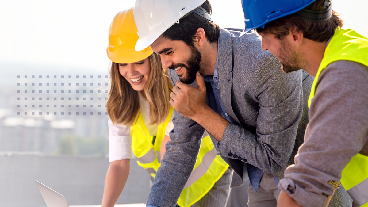 Three municipal broadband partners in hardhats smiling while viewing a laptop
