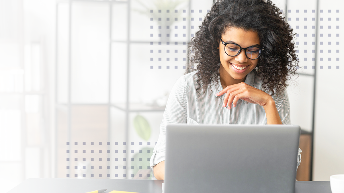 Smiling woman working on laptop in a bright, modern office space