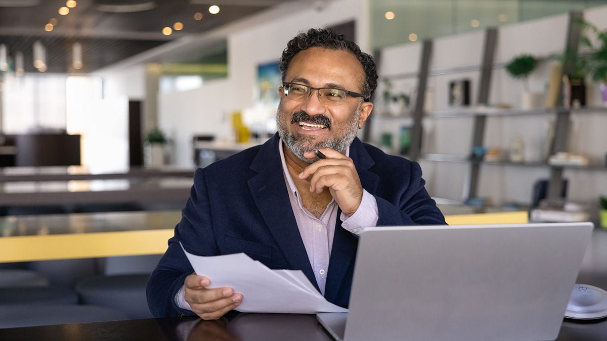 Smiling business man with laptop and paperwork