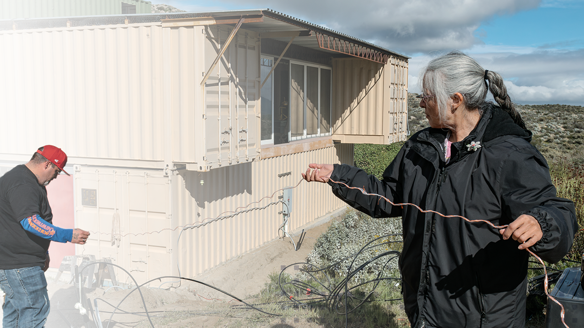 A man and woman from a tribal community holding network cables outside of a home