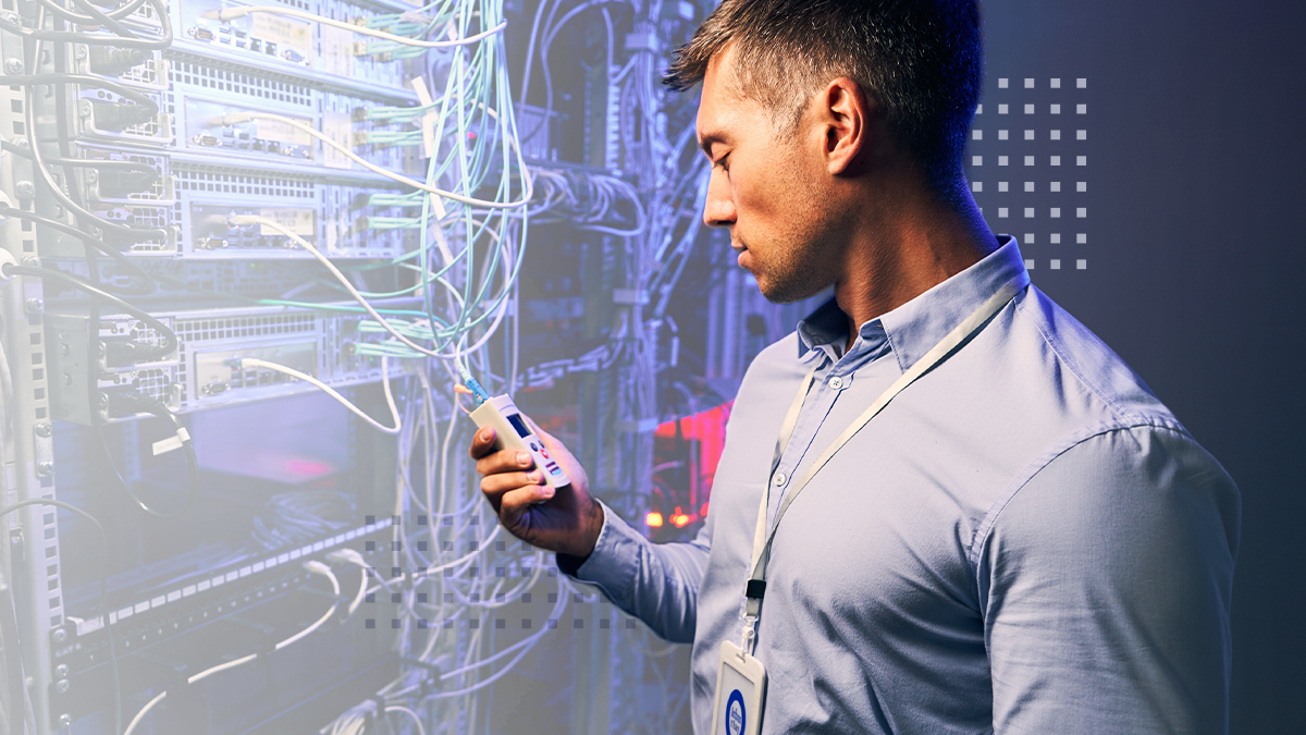 IT technician using reflectometer for testing fiber optic cables in data center