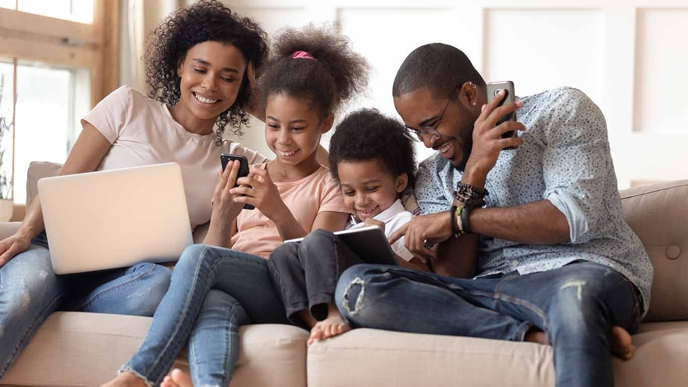 Family on couch using electronic devices