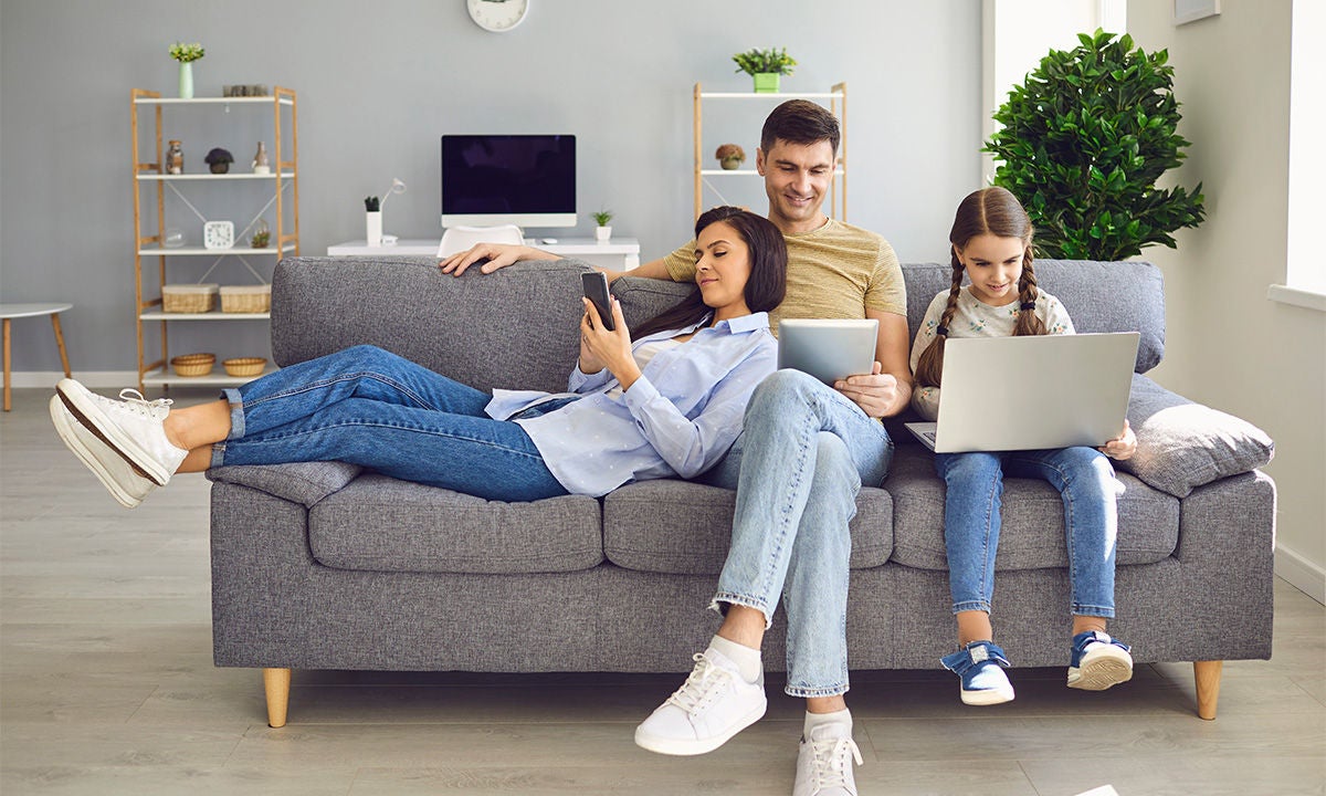 happy family with devices on sofa