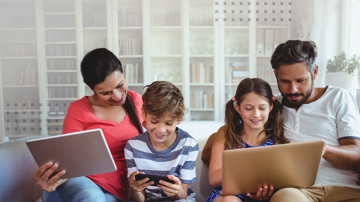 Happy family sitting on sofa and using laptop, mobile phone and digital tablet 