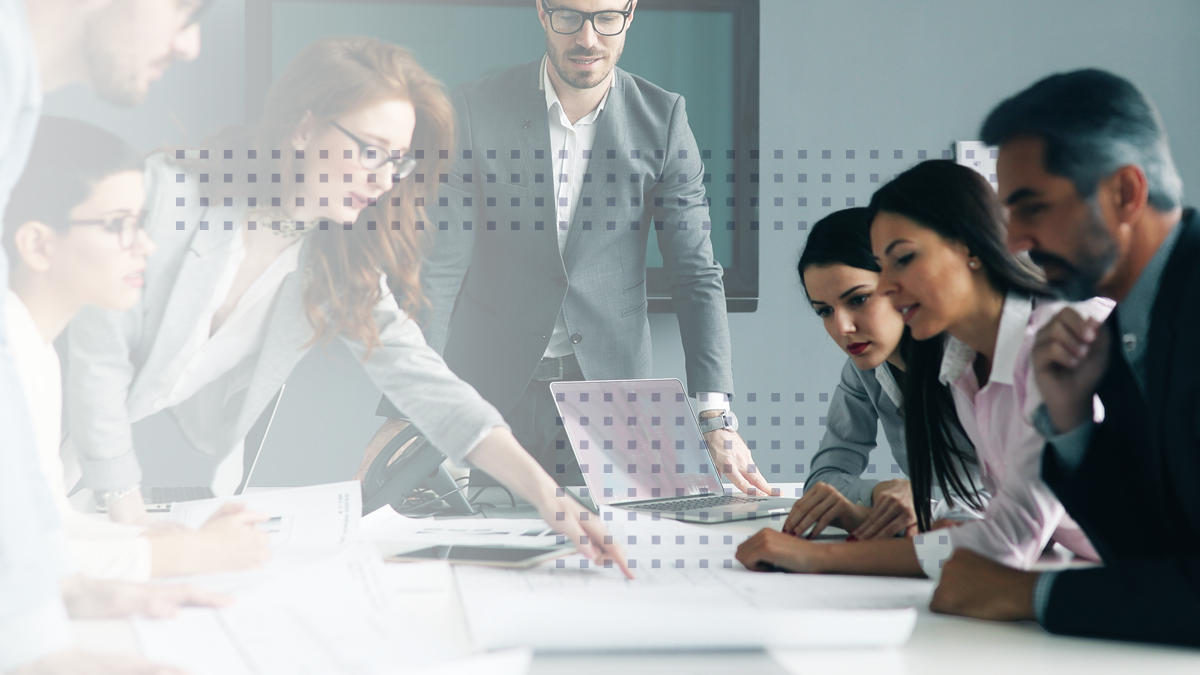 business colleagues are sitting at a table in conference room, collaborating on a project and pointing at the laptop screen, discussing ideas and strategies for success