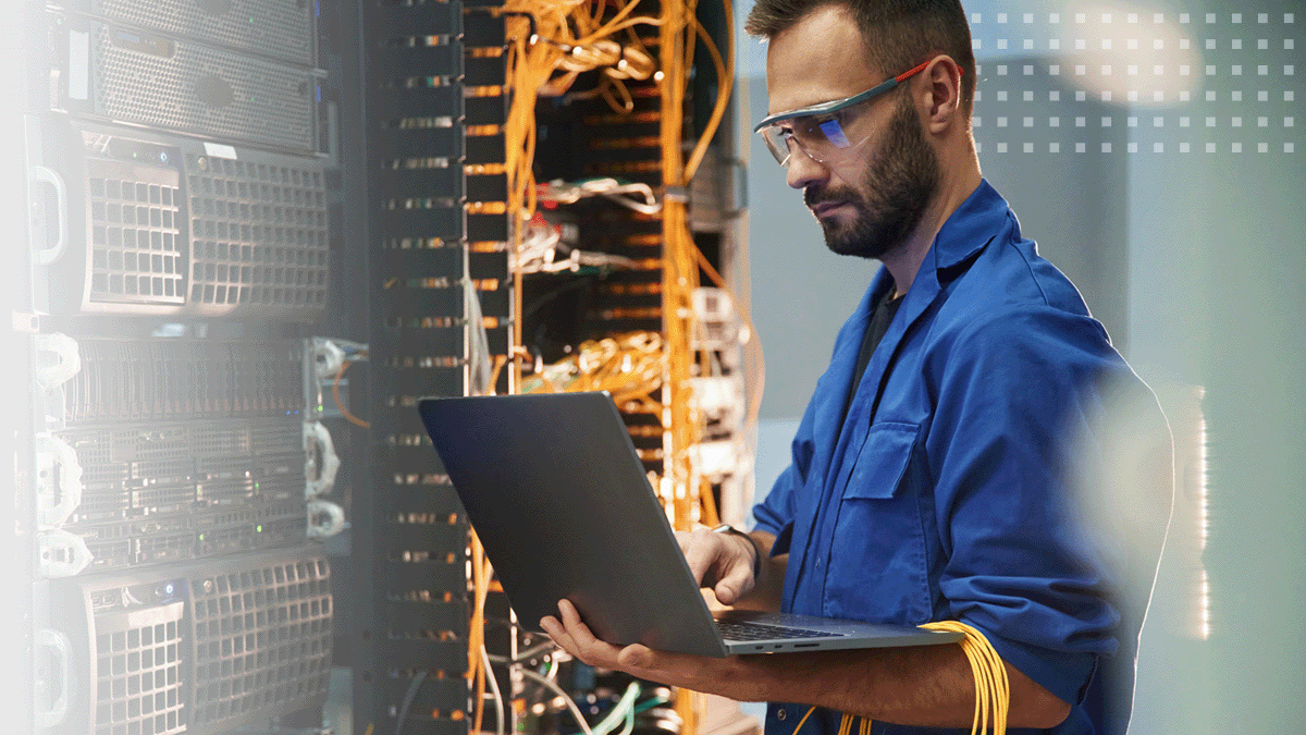 male engineer using laptop in computer server room